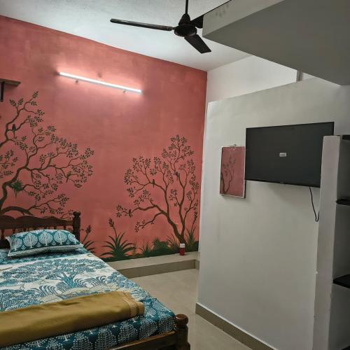 une chambre avec un lit et un mur avec une télévision dans l'établissement Thamara Auroville Homestay, à Pondichéry