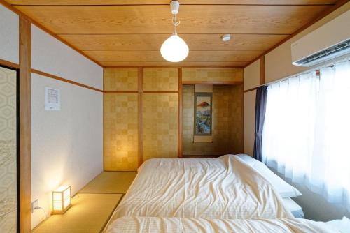 ein Schlafzimmer mit einem Bett mit Holzdecke in der Unterkunft 5 minutes on foot from the station, 20 minutes by train to Nagoya station, and it is a detached house, so families can use it with peace of mind! in Nagoya
