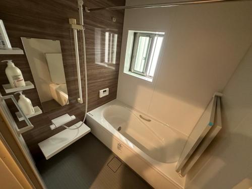 een badkamer met een bad, een wastafel en een spiegel bij 波音ハウス in Yugawara