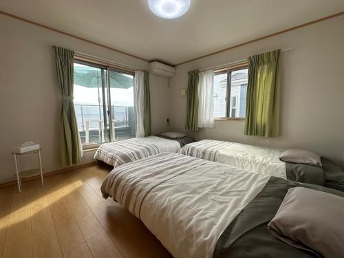 een slaapkamer met drie bedden en een raam bij 波音ハウス in Yugawara