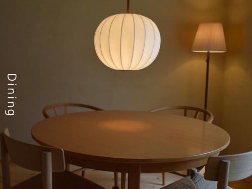 a dining room table with chairs and a light fixture at and farmクラインガルテン in Nirasaki