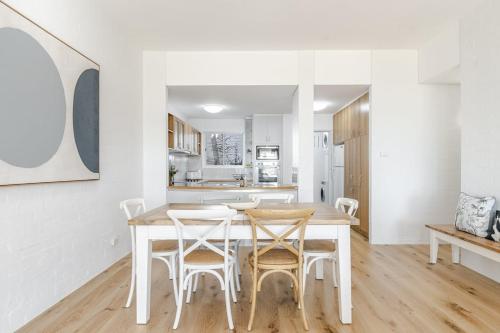 a white kitchen with a wooden table and chairs at Quarterdeck Unit 2 - Lennox Head in Lennox Head
