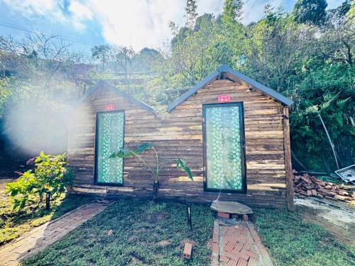 a small wooden house with two windows in the grass at Homestay26 in Bắc Yên