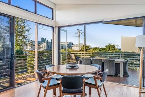 a dining room with a table and chairs and large windows at Sandy Feet in Lennox Head
