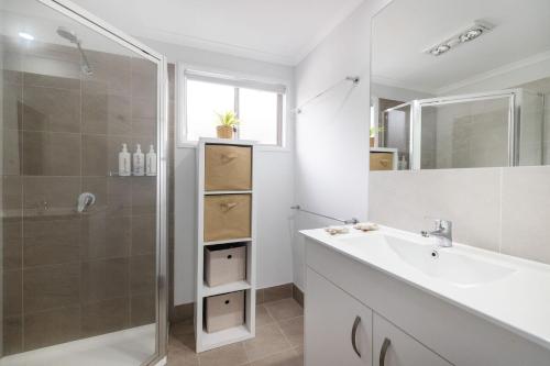 a bathroom with a shower and a sink and a mirror at Conjola Escapes in Green Island