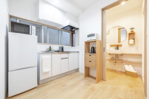 - une cuisine avec des placards blancs et un miroir dans l'établissement TaroTime Shinjuku Serene Japanese Cottage, à Tokyo