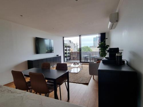 a living room with a table and chairs and a large window at It's Melbourne - by the Beach! in Melbourne
