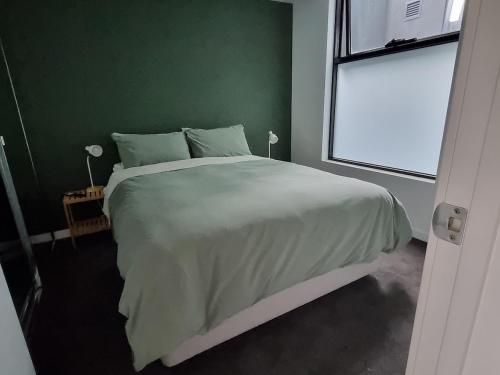 a bedroom with a large bed with a green wall at It's Melbourne - by the Beach! in Melbourne