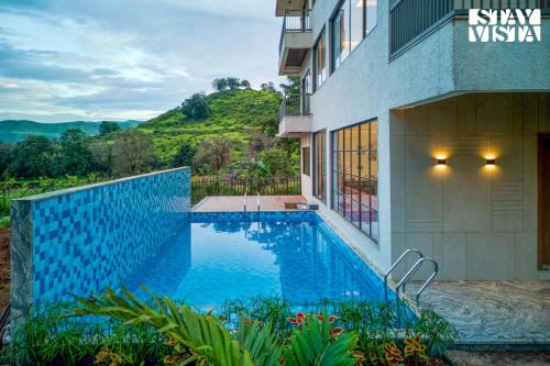 a swimming pool in front of a building at StayVista at Mount Brook with Mountain views, AC, Lawn in Igatpuri