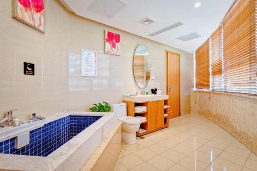 a bathroom with a tub and a toilet and a sink at Xian Song Of Apple Hot Spring Hotel in Xi'an