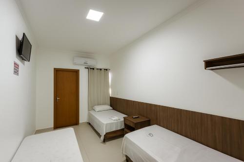 a small room with two beds and a television at Nova Jerusalém Hotel in Goiânia