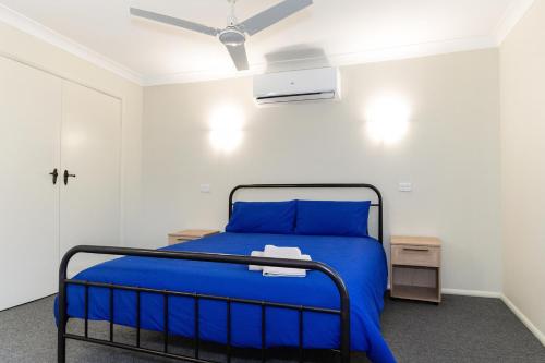 um quarto com uma cama azul e uma ventoinha de tecto em Brook Village em Muswellbrook