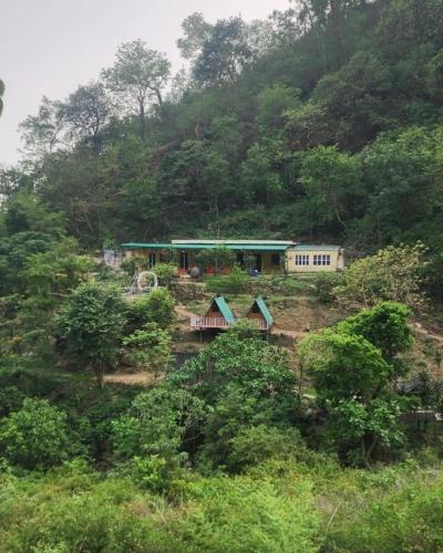 a house on the side of a hill with trees at Waterfall Camping A Hidden Paradise near Rishikesh in Rishīkesh