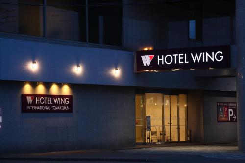 a building with a hotel wing sign at night at Hotel Wing International Tomakomai in Tomakomai