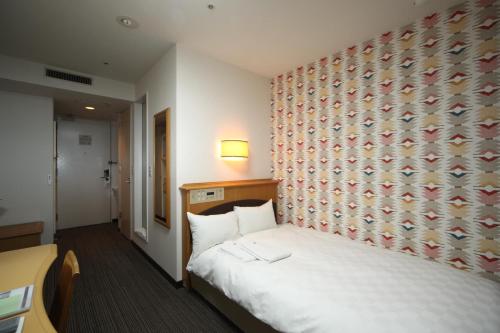 a hotel room with a bed and a wall at Hotel Wing International Tomakomai in Tomakomai