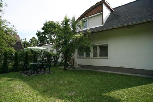 un patio con mesa, sillas y sombrilla en Sirály Apartman, en Balatonfűzfő