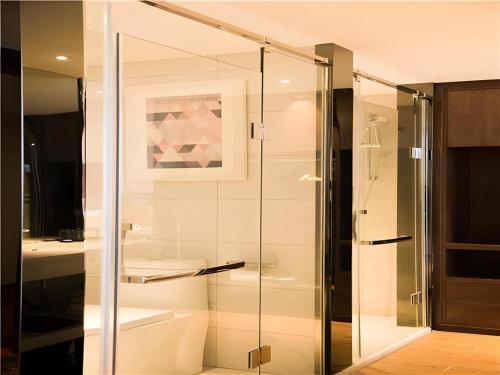 a bathroom with a glass shower with a toilet and a sink at Borrman Hotel Huanggang Wuxue Yuhu Road in Wuxue