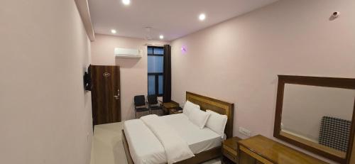 a bedroom with a white bed and a mirror at Hotel Nakshatra in Sawāi Mādhopur