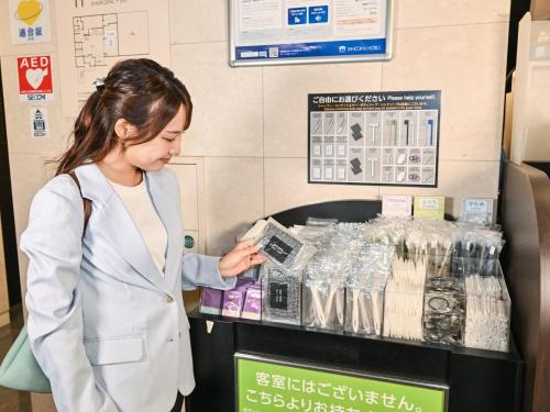 a woman standing in front of a cash register at Sanco Inn Nagoya Fushimi in Nagoya