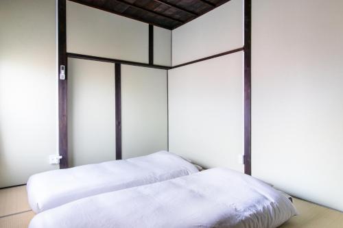 two beds in a room with white walls at Haguruma芦屋 in Ashiya