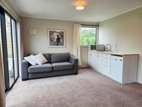 a living room with a couch and a kitchen at Saddleview Cottage-Horse and Trailer friendly in Mosgiel