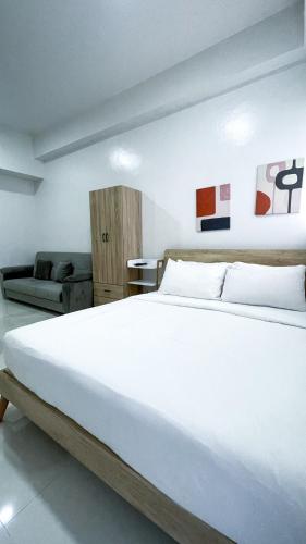 a bedroom with a large white bed and a couch at WV 32 Urban Scenic Studio in Sampong