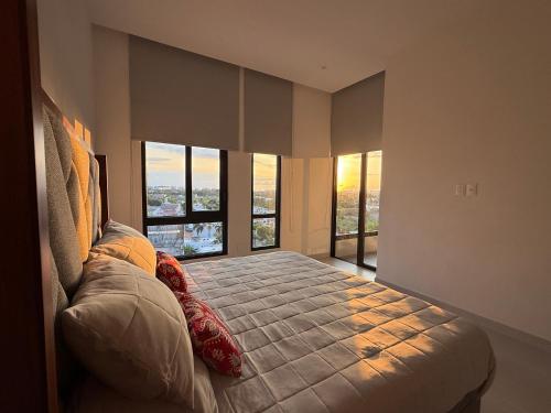 Un dormitorio con una cama grande con grandes ventanales. en Hermoso departamento 2 recámaras con alberca, en Nuevo Vallarta 