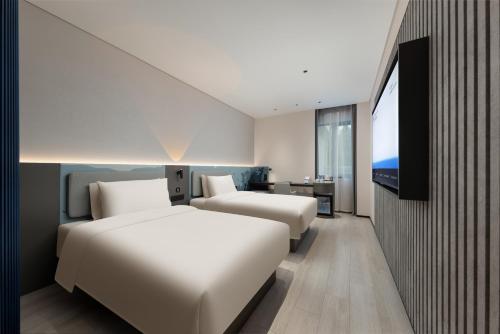 a hotel room with two beds and a flat screen tv at Shanghai Jiading Pingcheng Road Atour Light Hotel in Shanghai