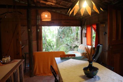 ein Esszimmer mit einem Tisch und einer Vase darauf in der Unterkunft Pedra Escondida in Imbituba