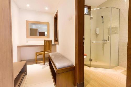 a bathroom with a shower with a bench and a glass door at Hotel Adilla Syariah Ambarukmo in Yogyakarta