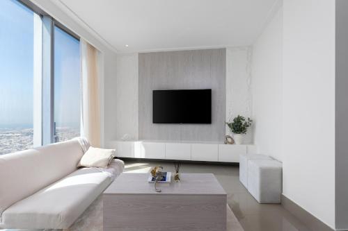 a living room with a white couch and a tv at Maison Privee - City Heights Retreat with Panoramic Skyline Views in Dubai