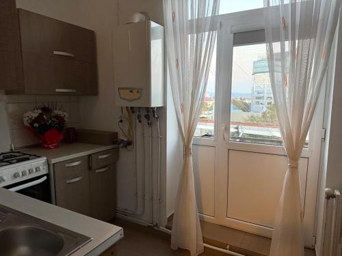 a kitchen with a window and a door with curtains at Nova Central Apartment in Bacău