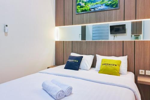 a bedroom with a large bed with yellow and blue pillows at Urbanview SANT Hotel Syariah near Stasiun Tegal in Tegal