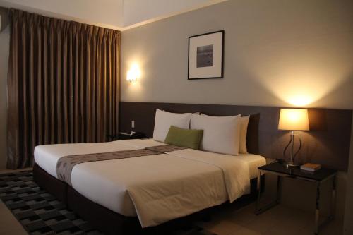 um quarto de hotel com uma cama grande e duas lâmpadas em Sequoia Hotel em Manila