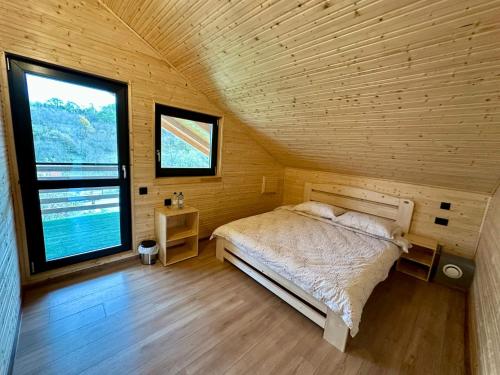 a bedroom with a bed in a wooden room with a window at Chalet Valisoara Cluj in Vălisoara