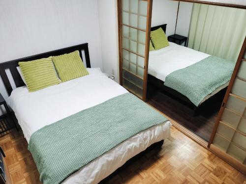 a bedroom with two beds and mirrors in it at Family Home Osaka Awaji Guest House in Osaka