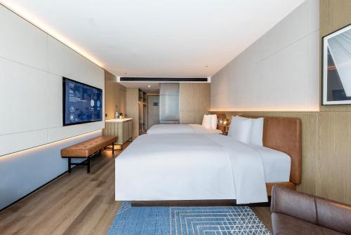 Una habitación de hotel con una cama grande y un televisor. en Four Points by Sheraton Yantai Zhifu, en Yantai