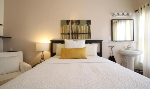 a bedroom with a bed with a yellow pillow and a sink at Hotel Royal in Long Beach