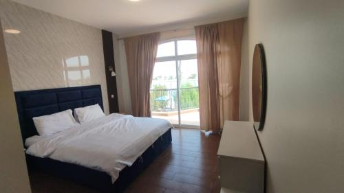 Un dormitorio con una cama y una ventana grande. en درة العروس فيلا بلويتش الازرق, en Durat Alarous