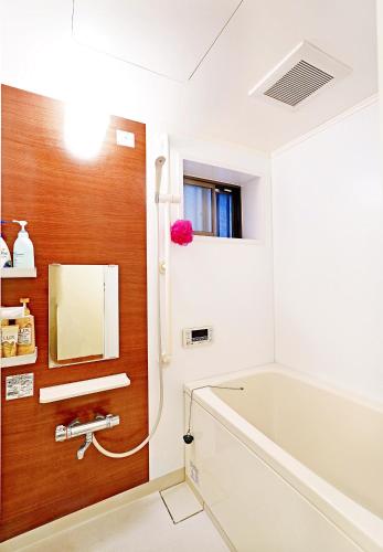 a bathroom with a tub and a sink and a mirror at Shalom 鶴橋 市中心地铁口徒步10秒可到民宿 地铁6分钟直达难波 大阪3条地铁交汇处 30分钟直达奈良 in Osaka