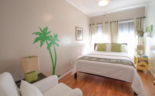 a white bedroom with a bed and a palm tree at Hotel Royal in Long Beach