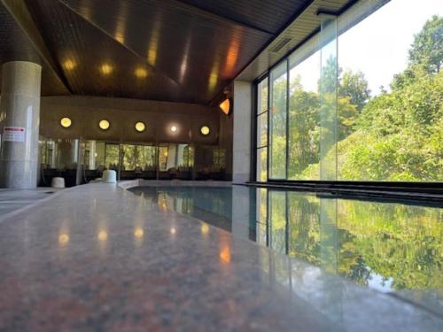 une piscine dans un immeuble avec une grande fenêtre dans l'établissement Zuien Country Club Century Fuji Course, à Manzawa