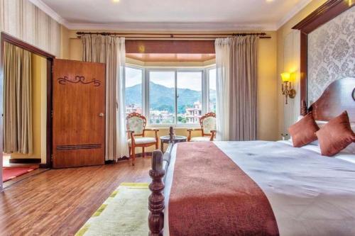 une chambre avec un grand lit et une grande fenêtre dans l'établissement Da Yatra Courtyard Hotel & Resort, à Pokhara