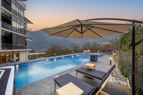 - une piscine avec un parasol à côté d'un bâtiment dans l'établissement Echor Himalayan Aurum Manali, à Manali