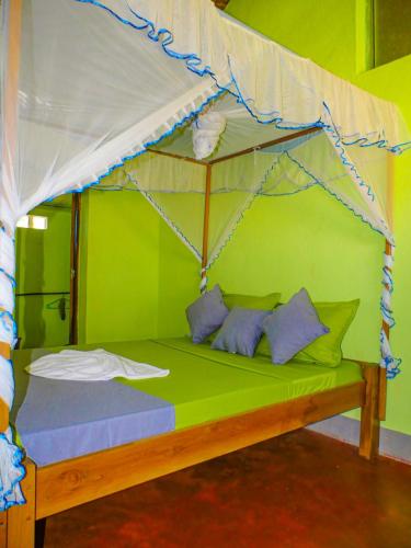 a bedroom with a canopy bed with blue pillows at Le Relais de Djangoa in Djangoa