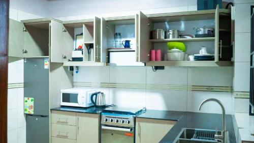 a kitchen with white cabinets and a microwave at Kigali Airport Stay Apartments in Kigali