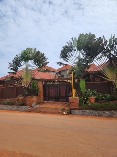 a house with a gate and two palm trees at Greg j & m suites in Kira