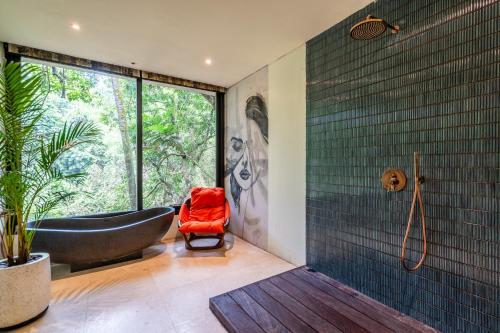 La salle de bains est pourvue d'une baignoire noire et d'une grande fenêtre. dans l'établissement Yara Wellness, à Munggu
