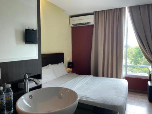 a bedroom with a bed and a sink and a tub at Zotel Business & Leisure Hotel in Kampong Tabuan