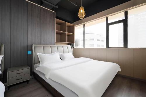 a bedroom with a large white bed and a window at Shanpanyisu Hotel in Chongqing